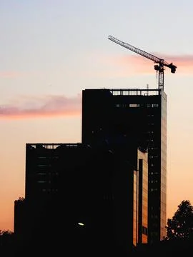 Sunset silhouette of skyscraper with crane Photos