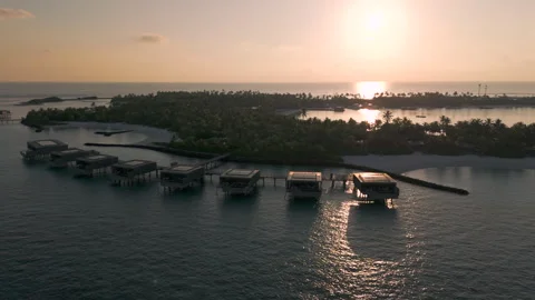 Sunset silhoutte view of luxury over water bunglows on a tropical island Stock Footage 309515871