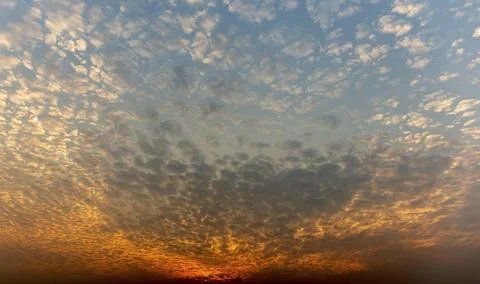The sunset sky is beautiful in orange, the clouds spread into cubes. Stock Photos