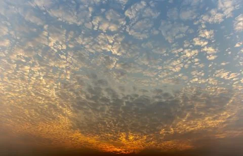 The sunset sky is beautiful in orange, the clouds spread into cubes. Stock Photos