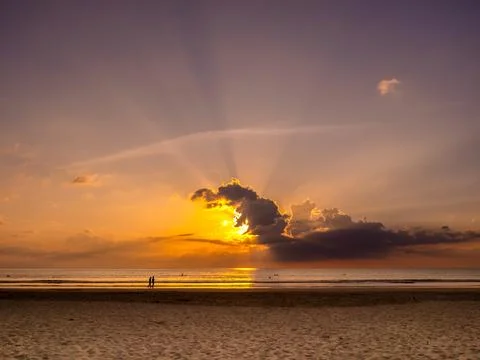 Sunset sky with beautiful sun rays behind the cloud over the sea water back.. Stock Photos