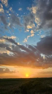 Sunset sky with clouds over dark landscape and horizon Stock Photos