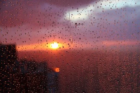 Sunset sky with clouds of the sea background seen through raindrops on glass Stock Photos