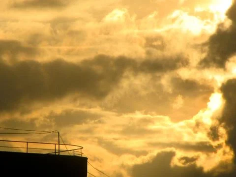 Sunset sky with clouds. The sun is setting behind the clouds. Stock Photos