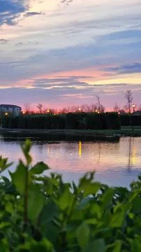 Sunset sky with colorful clouds over a river with plants Stock Photos