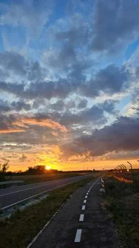 Sunset sky with colorful clouds over empty road Stock Photos