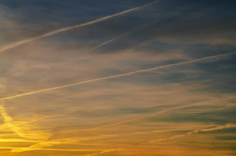 Sunset sky with contrails creating abstract patterns across the horizon Stock Photos