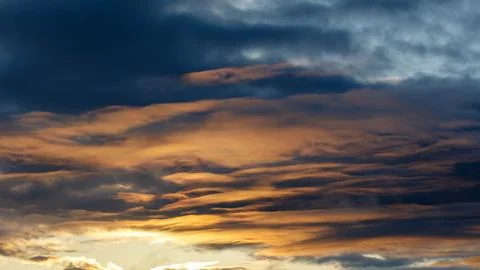 Sunset sky with dark blue and golden orange clouds Stock Photos