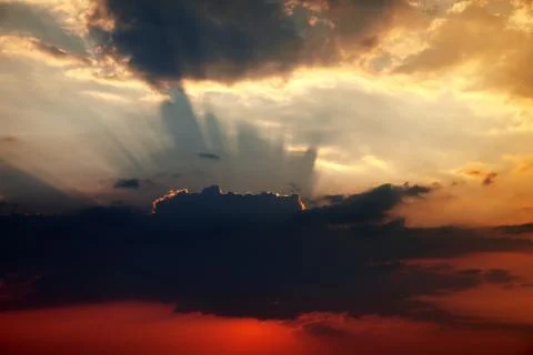 Sunset sky with dark clouds and sun rays Stock Photos