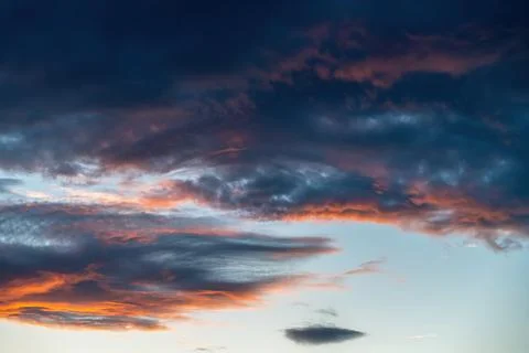 Sunset sky with dark clouds lit by orange hues, perfect for dramatic moods Stock Photos
