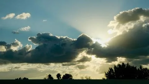 Sunset Sky With Dramatic Clouds Over Calm Horizon and Tree Silhouettes at Dusk Stock Photos