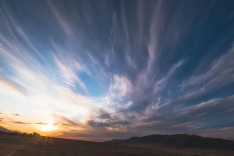Sunset sky with dramatic clouds over a wide mountain landscape. Sky backgroun Stock Photos