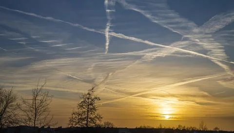 Sunset sky filled with intersecting airplane contrails Stock Photos