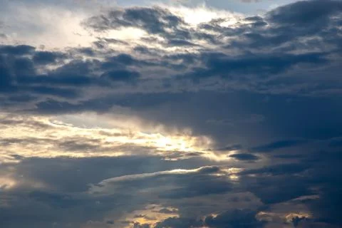 Sunset sky with layered clouds in various shades of blue, gray, and gold. A.. Stock Photos