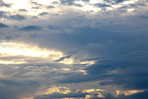 Sunset sky with layered clouds in various shades of blue, gray, and gold. A.. Stock Photos