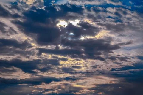Sunset sky with layered clouds in various shades of blue, gray, and gold. A.. Stock Photos