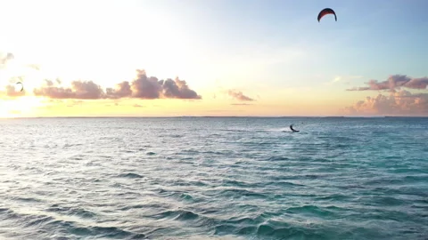 Sunset sky over the Indian Ocean bay with kiteboarders riding kiteboards with gr Video stock 260052466