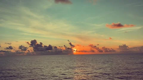Sunset sky over a serene ocean with vibrant clouds and soft waves creating .. 動画素材 338282602