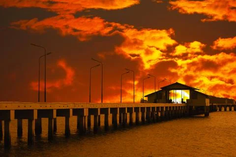 Sunset sky red cloud on pavilion on pier and silhouette light poles 写真素材