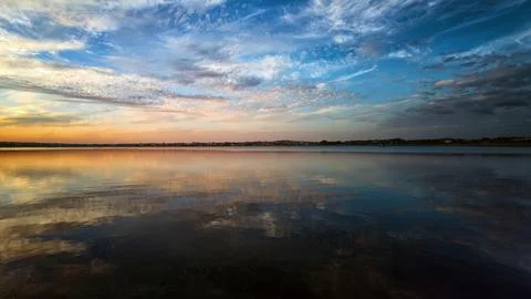 Sunset sky reflection on calm lake Stock Photos