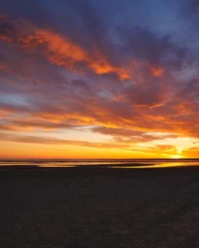 Sunset sky with reflections in water, sunlight and colored orange clouds. Stock Photos