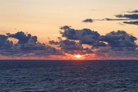Sunset sky with sun at sea. Dramatic sunset clouds in the Baltic Sea view fro Stock Photos