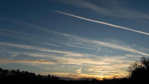 Sunset sky with wispy clouds and airplane contrails 스톡 사진