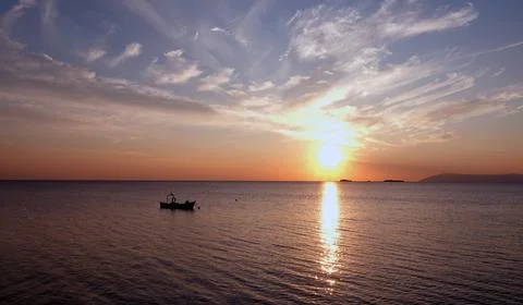 The sunset on the skyline over the sea with tiny shadow fishing boat Foto stock
