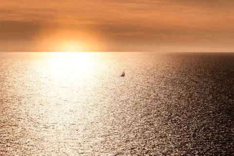 Sunset with a small sailboat Stock Photos