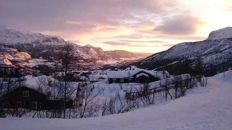Sunset in snow covered mountains casting colored light on the the valley Stock Photos