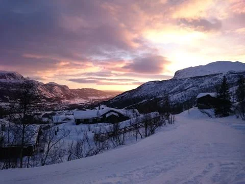 Sunset in snow covered mountains casting colored light on the the valley Stock Photos