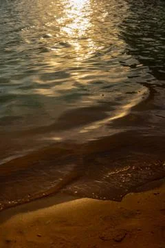 Sunset, soft wave of the sea on a sandy beach Stock Photos