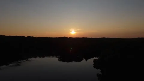 Sunset starting with on lake with reflection of trees goes up to reveal sunset Stock Footage 251565024