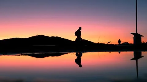 Sunset Stroll: Reflections of People Walking by a Puddle Foto stock