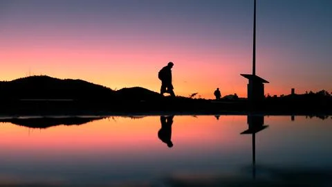Sunset Stroll: Reflections of People Walking by a Puddle Foto stock