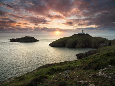 Sunset at Strumble Head Lighthouse with orange clouds, Pembrokeshire, Wales Stock Photos