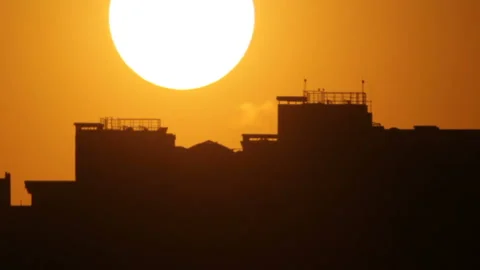 Sunset sun behind dark silhouette of building Stockbeeldmateriaal 120006903