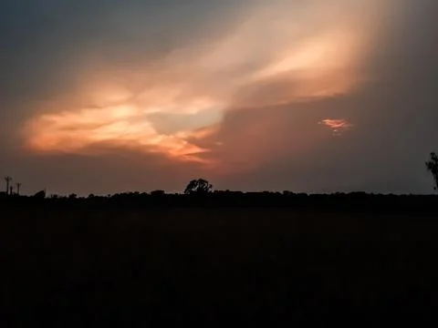 At sunset the sun is covered with black clouds and light is shining through i Stock Photos