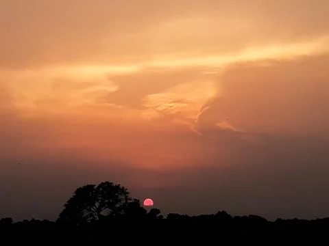 At sunset the sun is covered with black clouds and light is shining through i Stock Photos