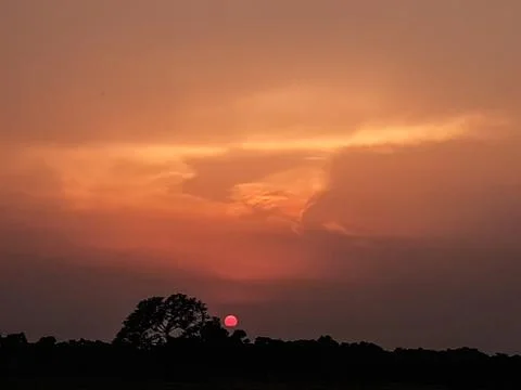At sunset the sun is covered with black clouds and light is shining through i Stock Photos