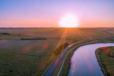 Sunset with sun flare over river and fields - aerial view 스톡 사진