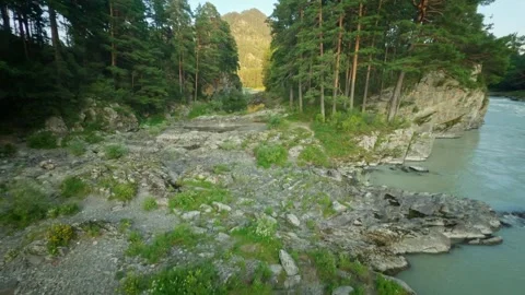 The sunset sun illuminates the mountains and the turbulent river. The girl Stock Footage 278366445