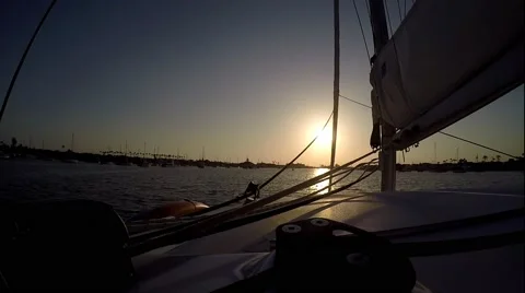 Sunset  with sun on jib sheet sailing catamaran motoring into harbor. Stock Footage 67580273