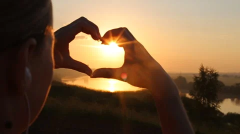 Sunset sun shining through heart shaped hands Stock Footage 64691583