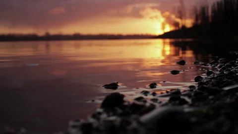 Sunset,on the surface of the water on curving river Coast with stones Stock Footage 129974920