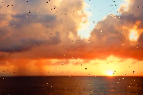 Sunset with tall clouds seen through a raindrop covered window. Stock Photos