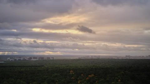 Sunset through dark rain clouds over the autumn forest, time-lapse. Sun and r Stock Photos