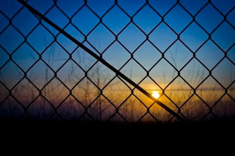 Sunset through the fence Stock-Fotos