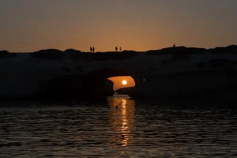 Sunset through Rock Arch over Water Stock-Fotos