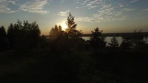 Sunset through the trees on the river bank. Aerial pan. 스톡 동영상 64804944